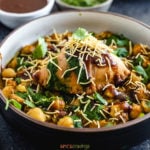 samosa and chana masala in bowl topped with chutney and sev