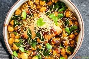 samosa chaat in bowl garnished with thin sev, cilantro and chutney