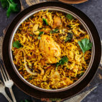 Top shot of chicken biryani in black bowl with forks on the side
