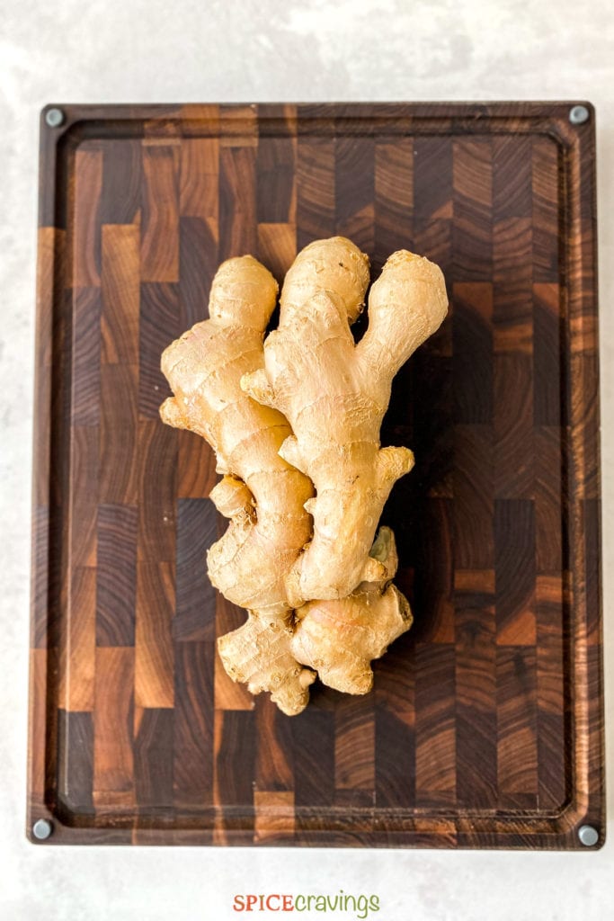 two fresh ginger root on wood cutting board