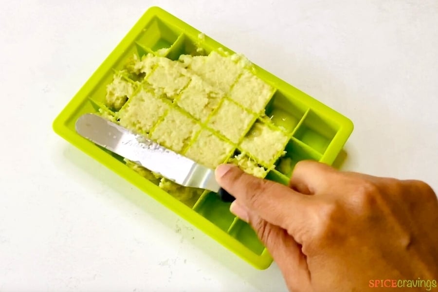 hand spreading ginger paste in ice cube tray with offset spatula
