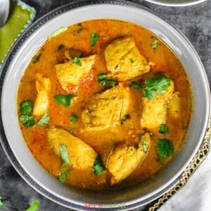Chicken curry in gray bowl garnished with cilantro leaves