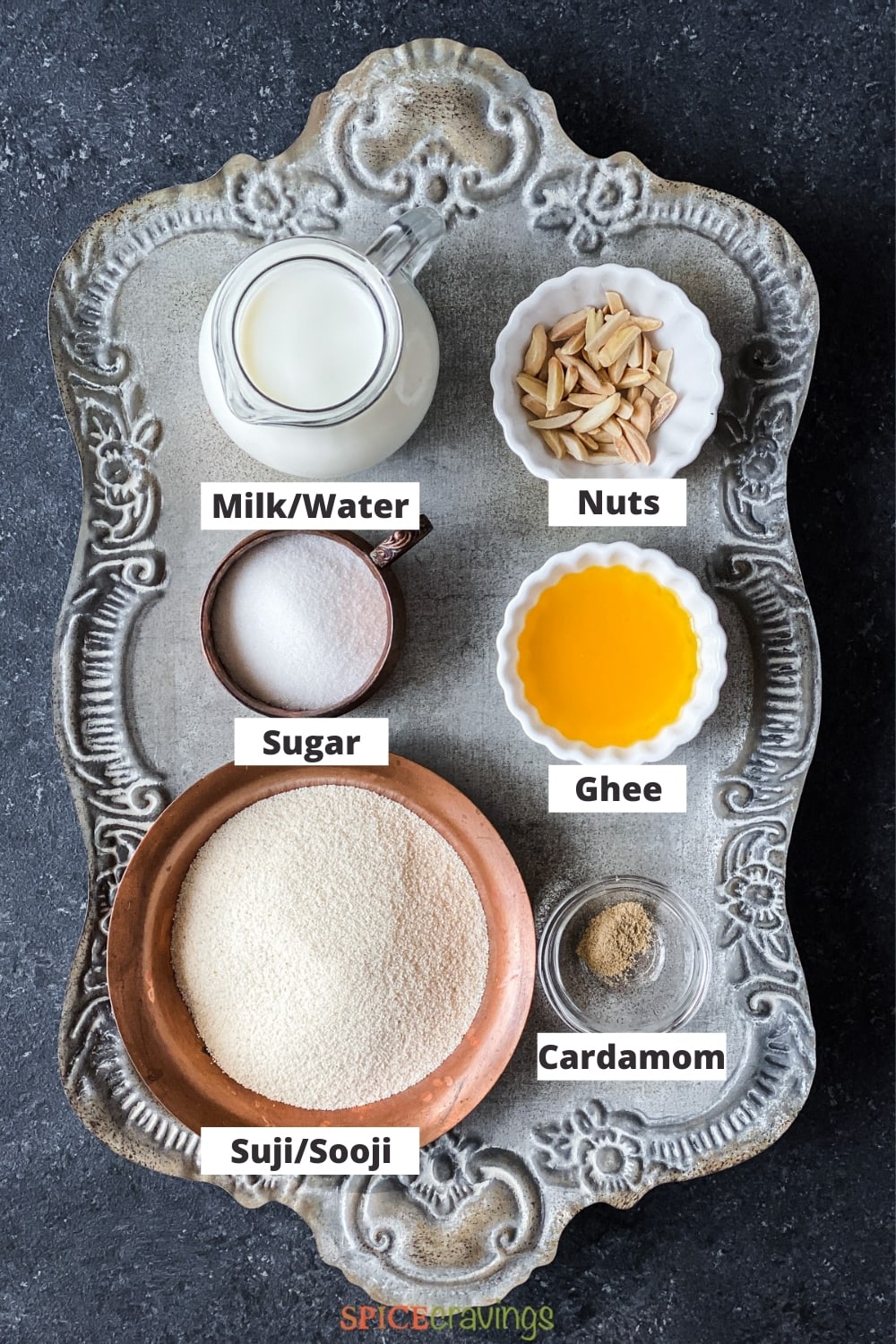 Milk, sugar, ghee, nuts, suji (semolina) on silver metal tray