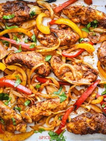 Mexican spiced chicken, peppers and onion on baking sheet