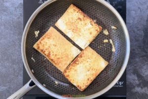 Tofu steaks browning in a skillet