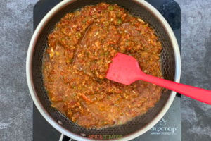 Tomato based sauce in a skillet with red spatula