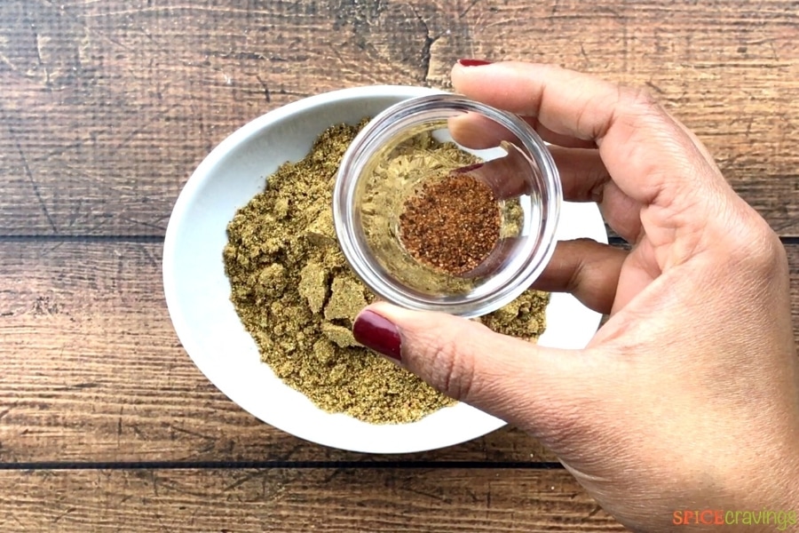 Holding a small bowl of ground nutmeg over a big bowl of spices