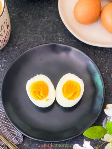 Boiled egg cut in half on a black plate