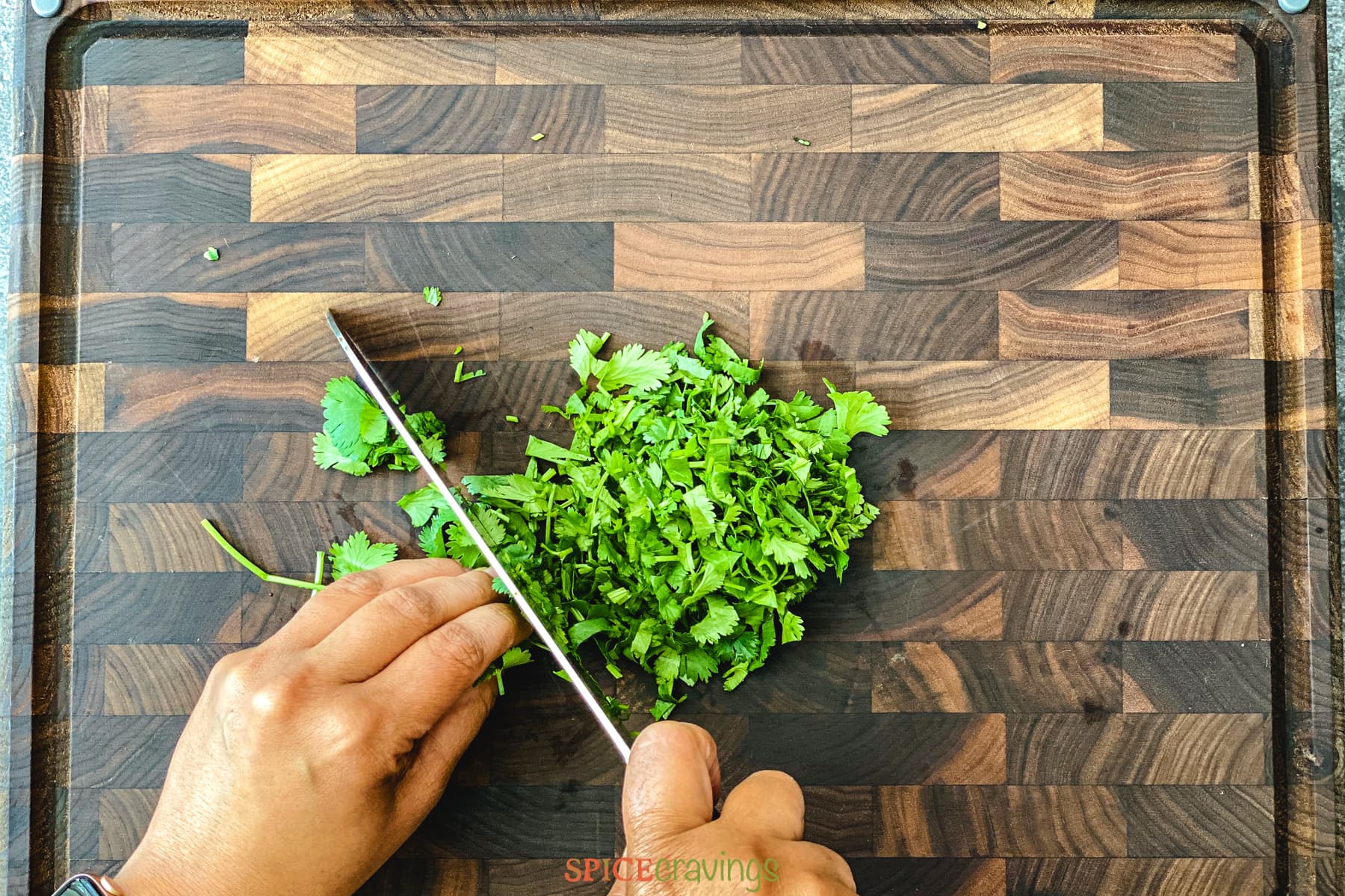 two hands chopping cilantro with knife