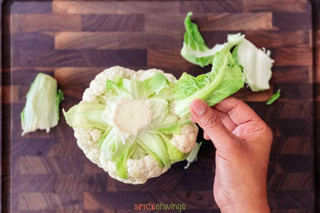 hand removing leaves from cauliflower head