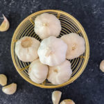six whole garlic heads in wooden basket