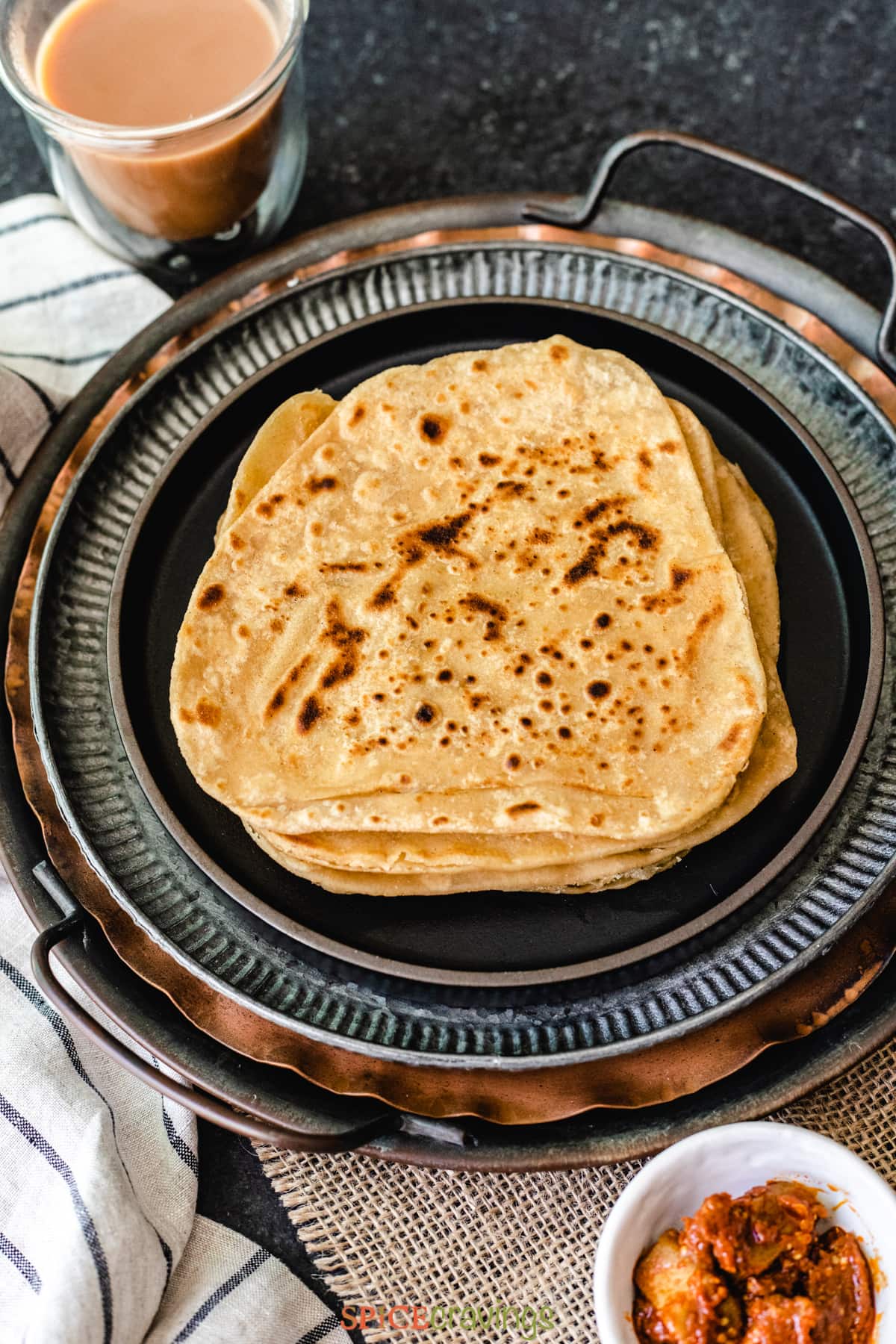 Stack of parathas with chai and pickle on the side