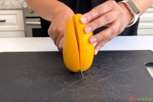 cutting large cheek from mango with a knife