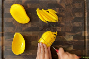 two hands dicing mango with a knife
