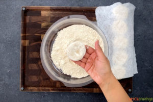 Coating the dough ball in flour before rolling paratha