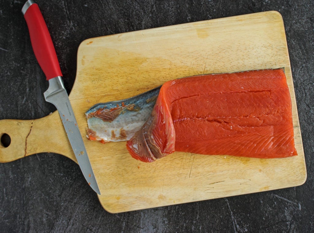 Removing skin from salmon on a wooden cutting board