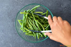 green beans being tossed with seasonings above