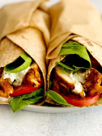 Two chicken shawarma wraps with spinach and tomato