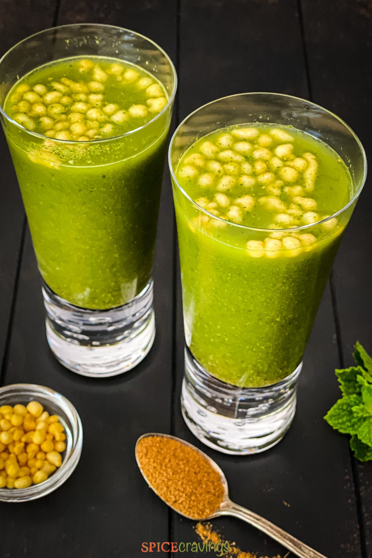 Two glasses of green jaljeera drink made with cumin