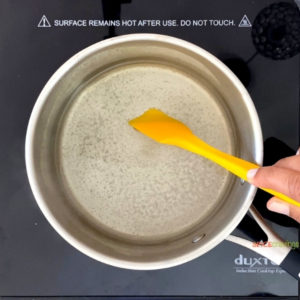 Stirring water and sugar in sauce pan with yellow spatula