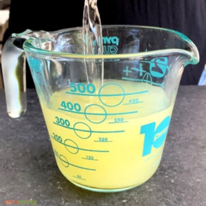 Adding simple syrup to lemon juice in measuring cup
