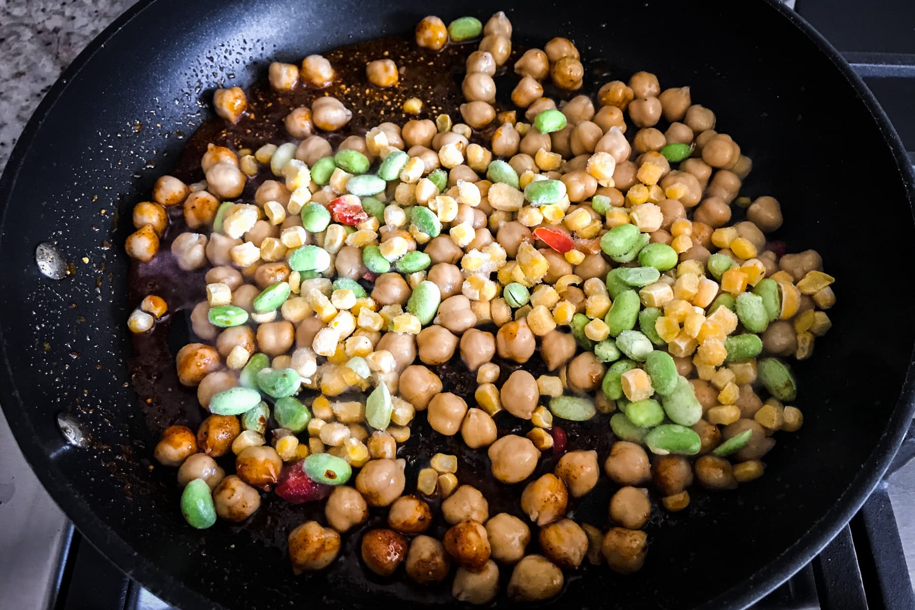 Frozen soycutash mix along with chickpeas in pan