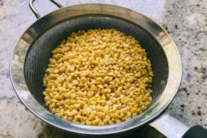 Rinsed split mung beans (moong dal) in a wire sieve