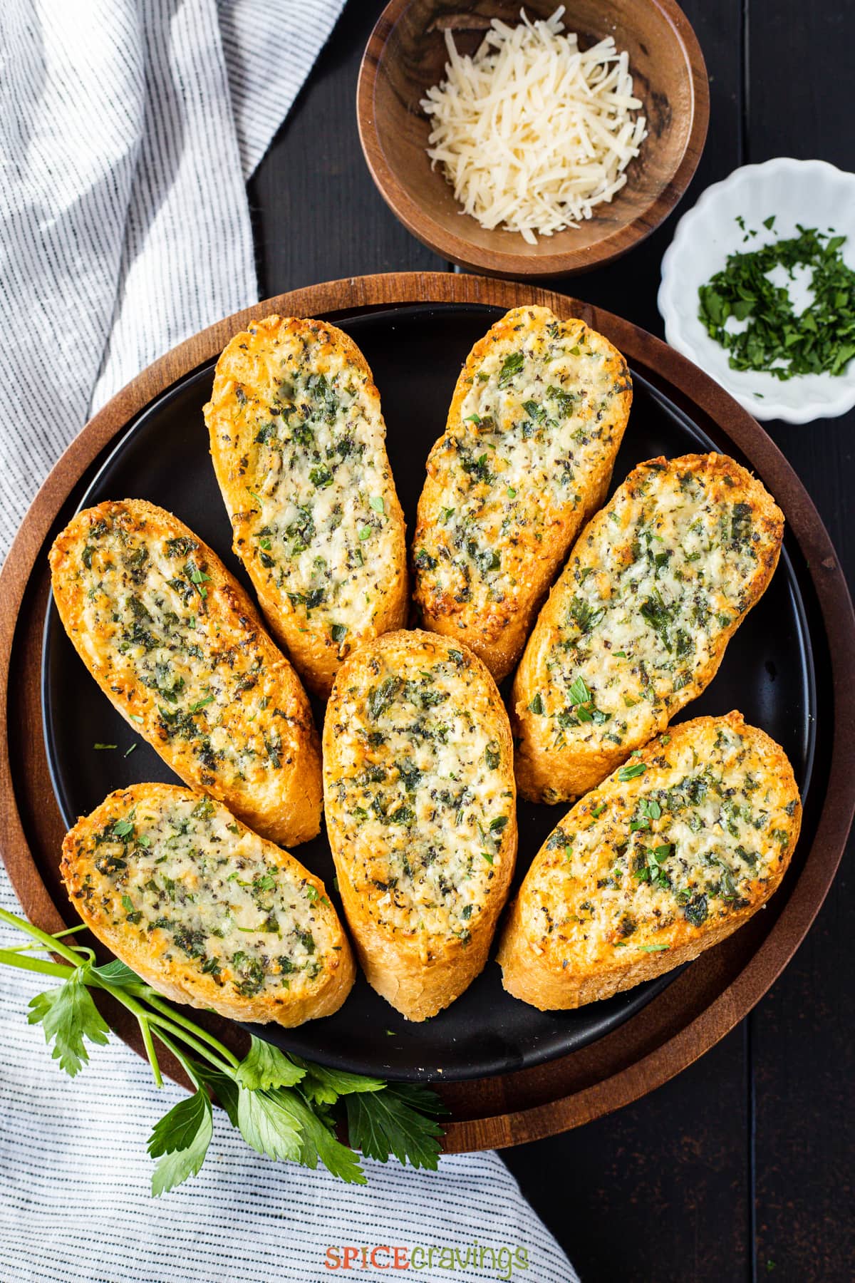 air fryer garlic bread on a black plate next to bowls of cheese and parsley