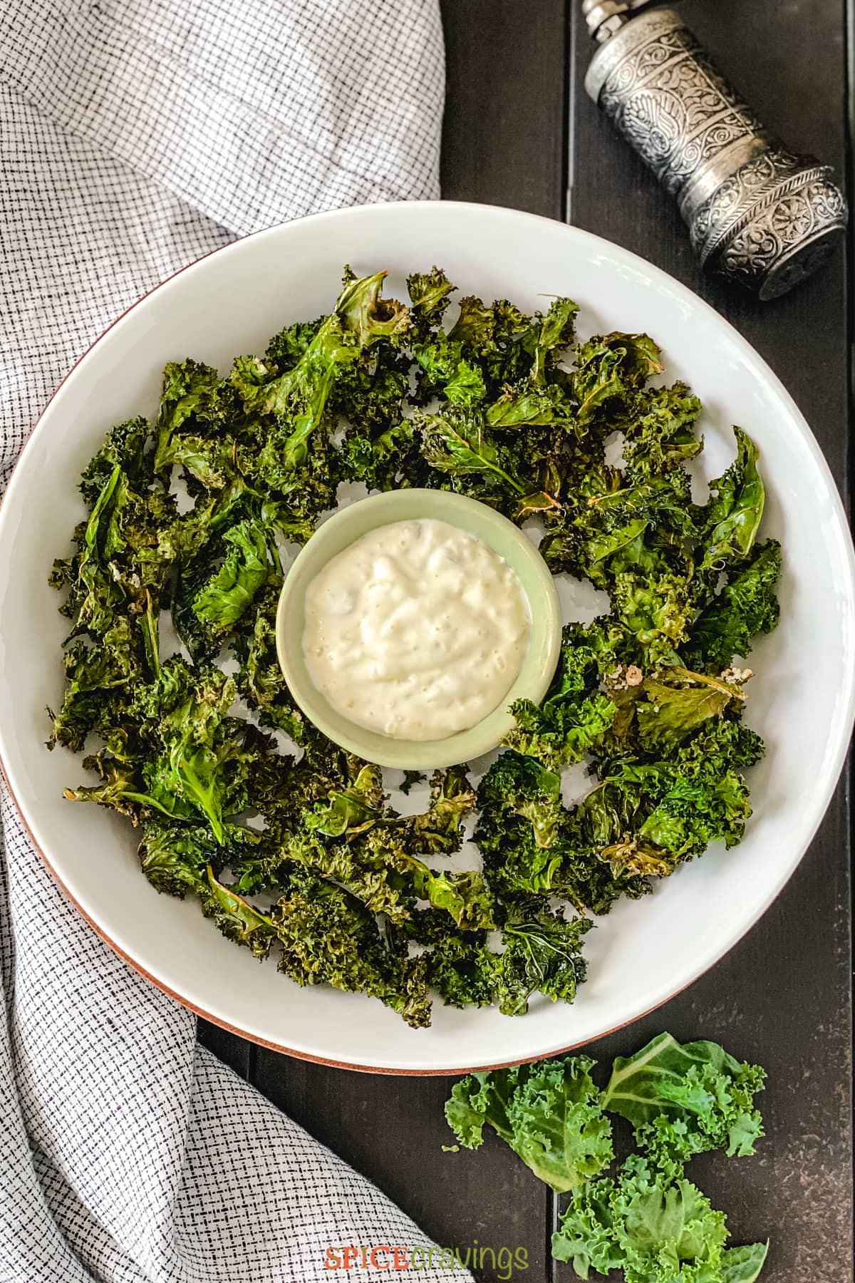 Kale chips in white bowl with lemon sauce in middle