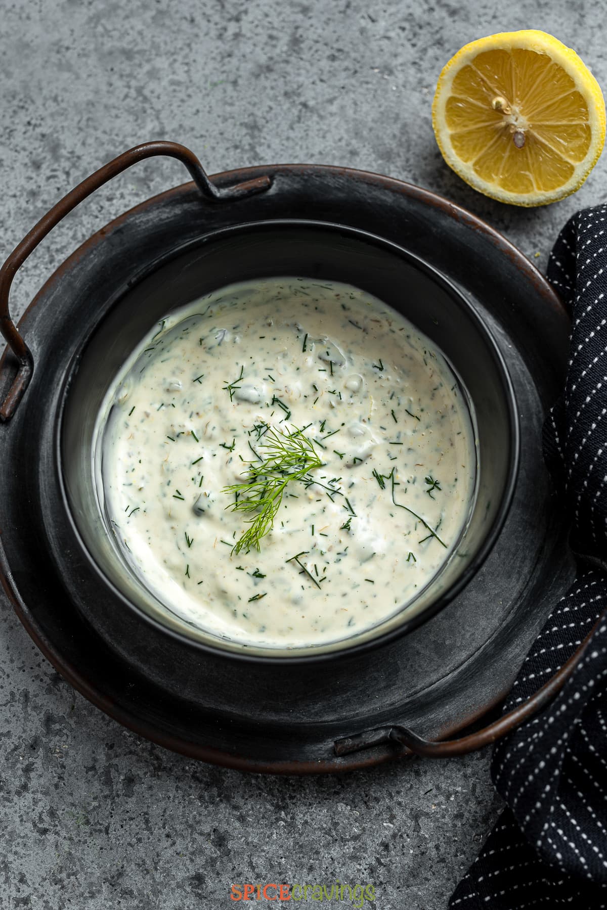 lemon caper sauce in a serving bowl garnished with fresh dill next to half a lemon
