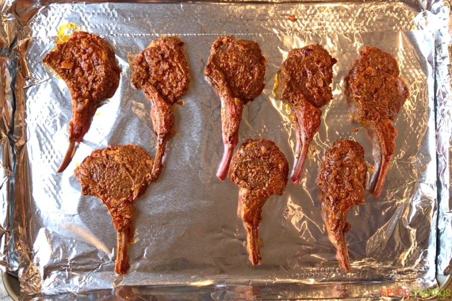 marinated lamb chops spread on baking sheet lined with aluminum foil