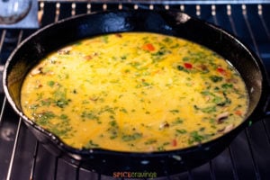 Egg frittata in skillet placed in the oven