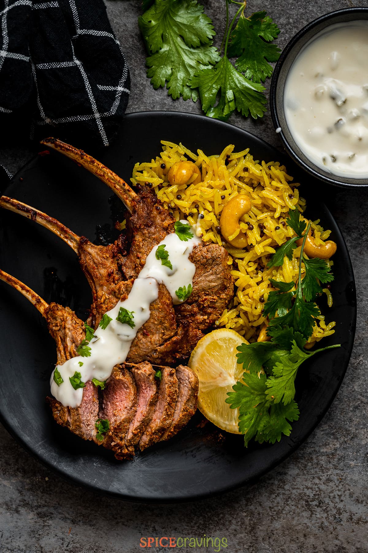three lamb chops topped with tzatziki with saffron rice, lemon wedges on plate