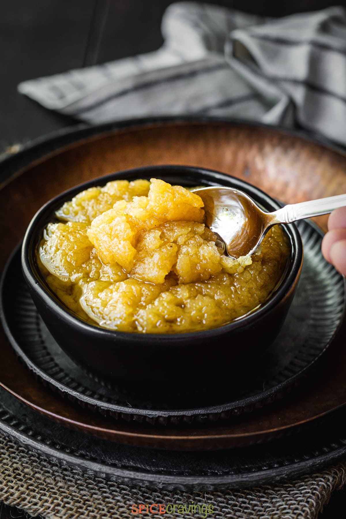 Spoon lifting halwa from a black bowl