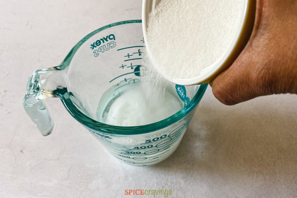 Adding sugar in measuring cup with water