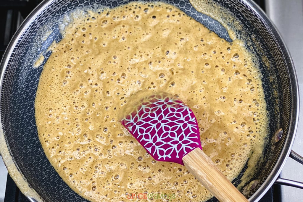 Stirring halwa in pan with purple spatula