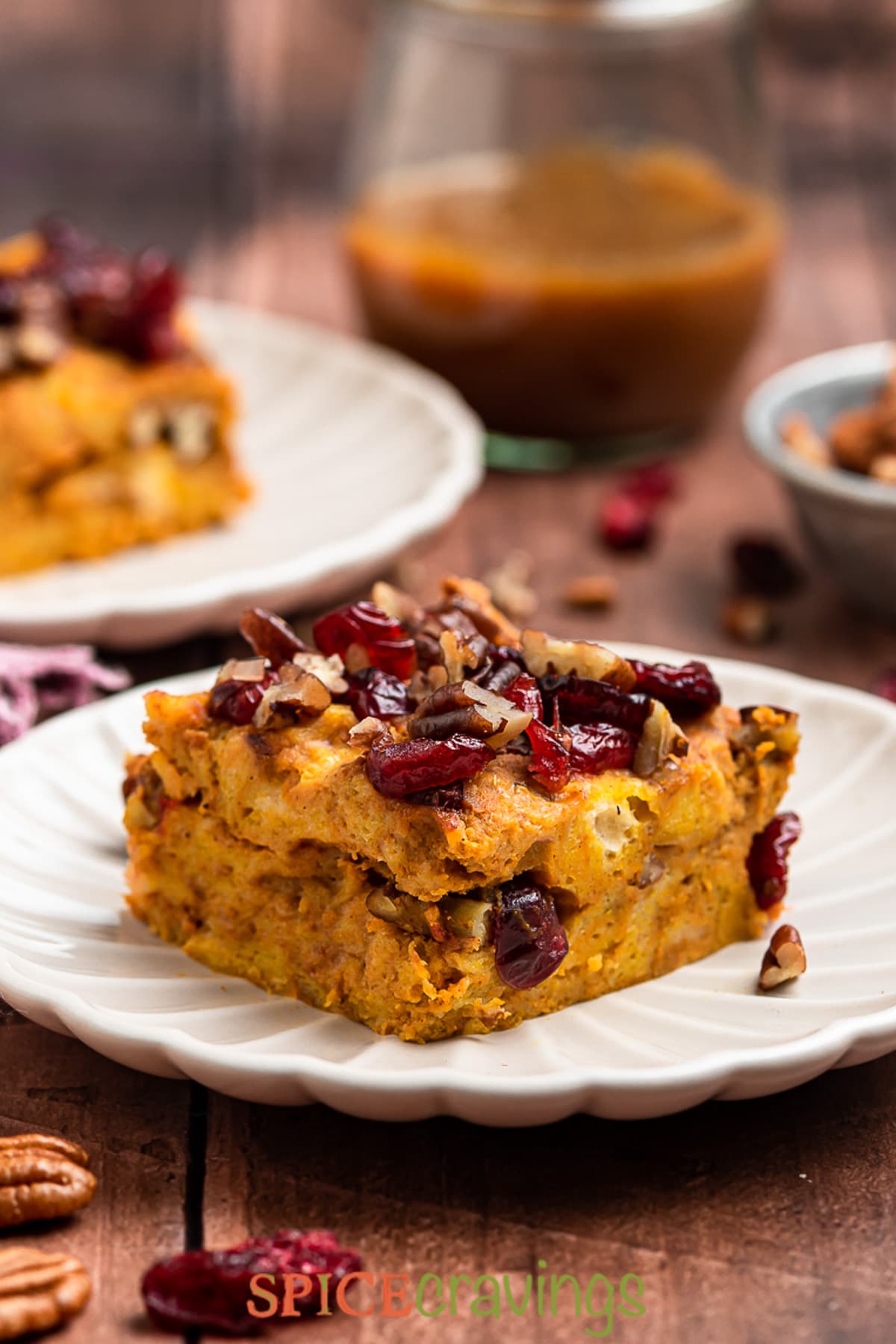 Slice of bread pudding with pumpkin, topped with pecans and cranberries