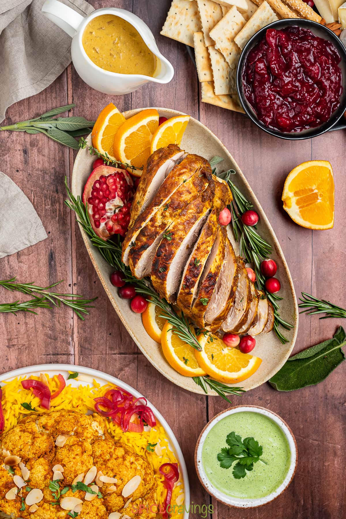 sliced turkey breast on platter with orange slices, cranberries and rosemary