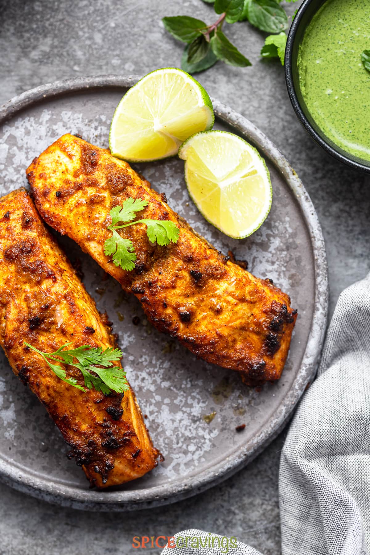 two tandoori salmon steaks on gray plate with lime wedges