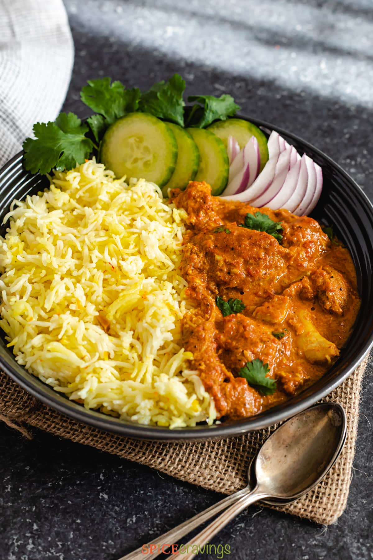 bowl of saffron rice, butter chicken, and fresh cucumber and red onion