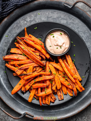 Air fried carrot fries with sriracha mayo on stacked black plate