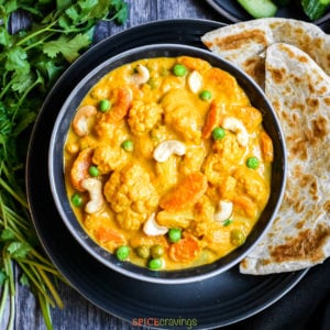 Assorted vegetables in yellow curry with side of paratha