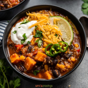 overhead of a bowl of instant pot vegetarian chili garnished with cheese, sour cream, jalapeño, and lime