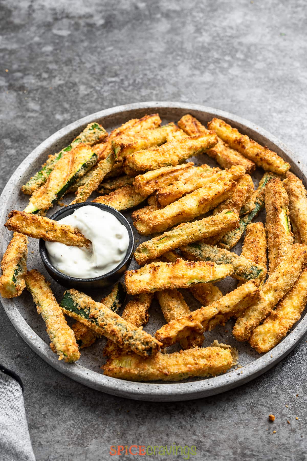 air fried zucchini sticks on large platter with tartar sauce on side