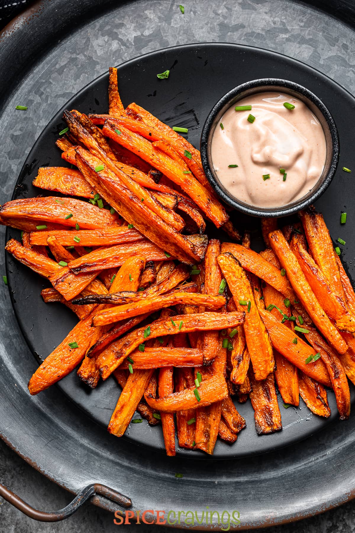 Roasted air fried carrot fries with dipping sauce on black plate