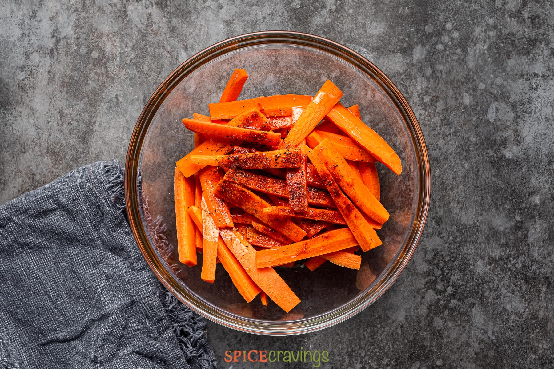 Carrot sticks on glass bowl topped with oil and spices