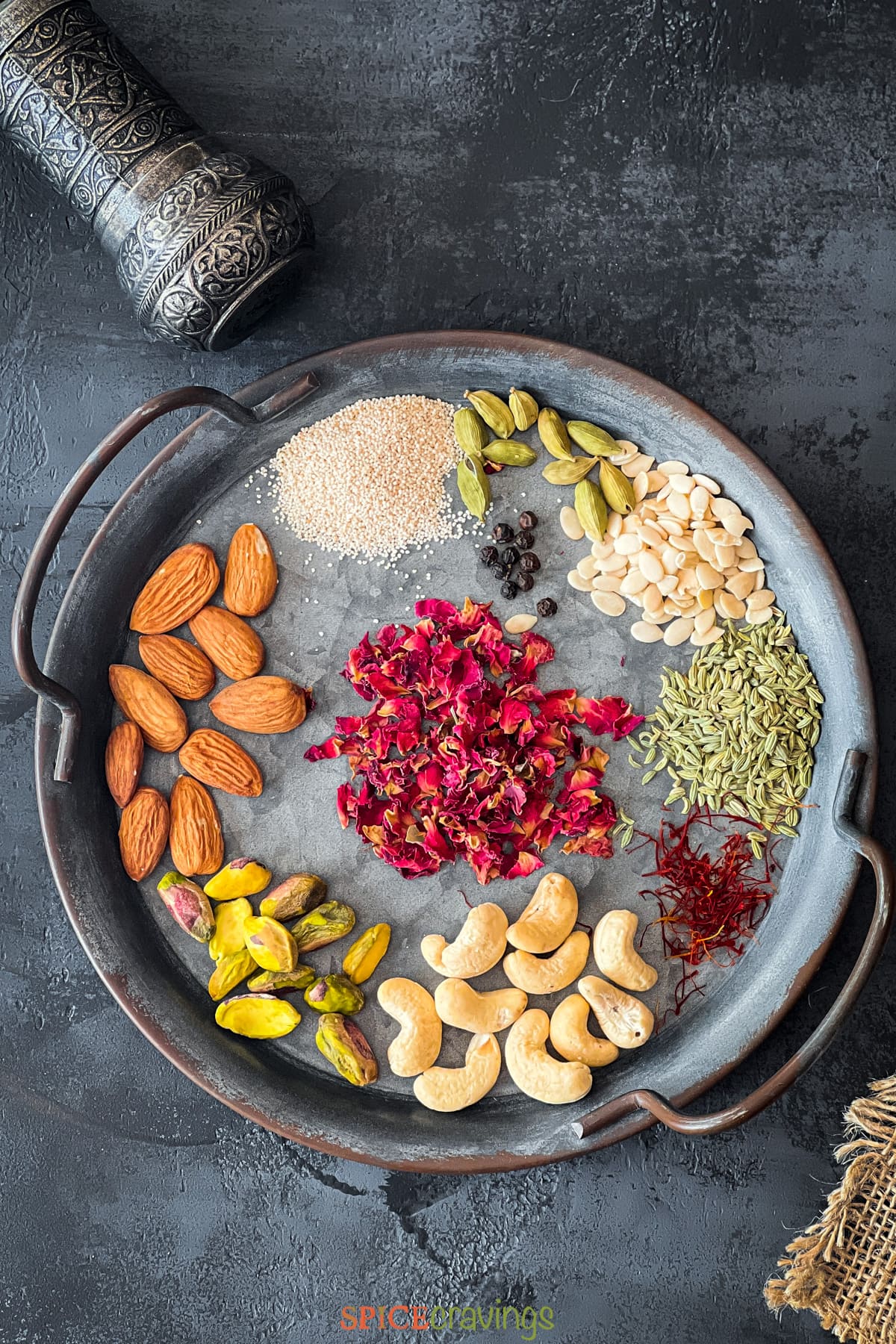 Metal plate with rose petals, nuts, seeds and whole spices