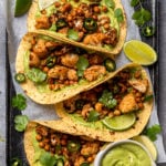 four roasted cauliflower tacos on baking sheet with green goddess on side
