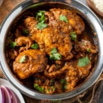 chicken vindaloo in copper bowl, garnished with cilantro leaves
