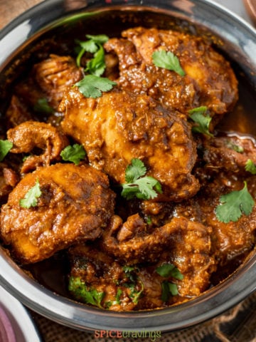 chicken vindaloo in copper bowl, garnished with cilantro leaves